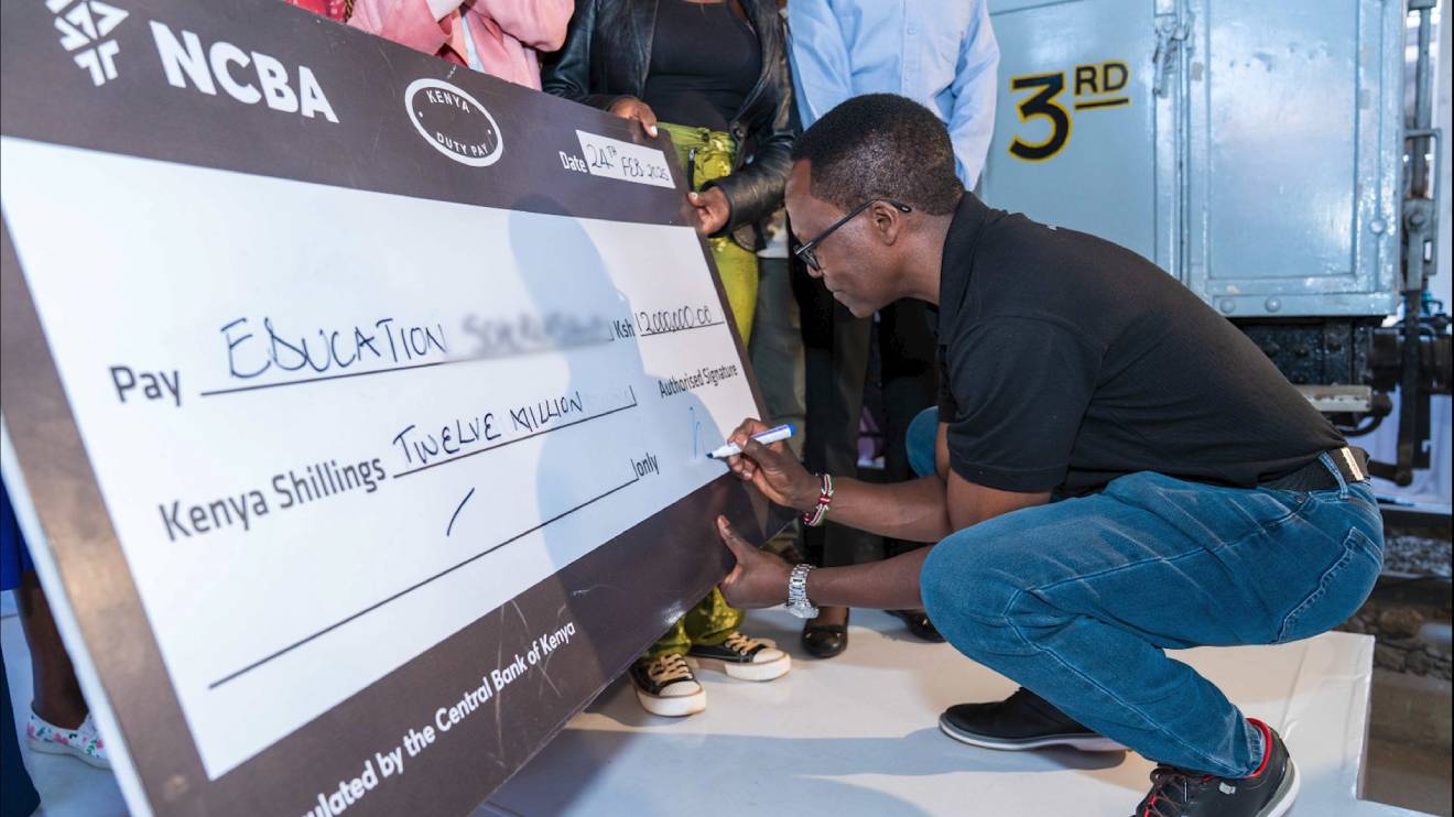 John Gachora signing a dummy cheque of Sh12 million. PHOTO/COURTESY